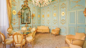 A room with a glass dining table surrounded by ornate chairs, a sofa, and a chandelier. - Canal View San Marco Rialto -Dogaressa Palace 1872 (Venezia)