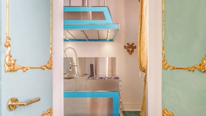 A kitchen with a blue and white color scheme, stainless steel appliances, and gold ornate door frames. - Canal View San Marco Rialto -Dogaressa Palace 1872 (Venezia)