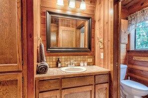 Ein Badezimmer aus Holz mit einem großen Spiegel, einem Waschbecken und einer Toilette.