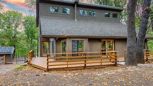 A modern two-story house with a wooden deck and large windows.