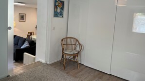 A room with a white wardrobe, a wicker chair, a small rug, and a painting on the wall. - Spacious and quiet  1-bedroom  place in Munich. Fully equipped sleeps 7 guests! (Munich)