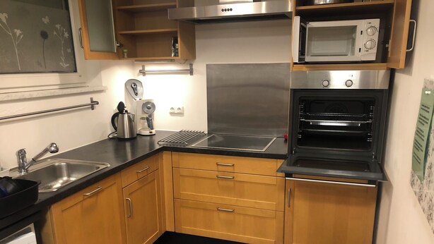 A compact kitchen with wooden cabinets, a stainless steel range, a microwave, and a built-in oven. - Spacious and quiet  1-bedroom  place in Munich. Fully equipped sleeps 7 guests! (Munich)