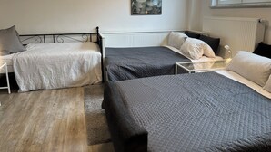 A bedroom with two beds, a radiator, a window with frosted glass, and a poster on the wall. - Spacious and quiet  1-bedroom  place in Munich. Fully equipped sleeps 7 guests! (Munich)