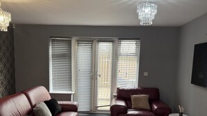 Un salon avec deux canapés en cuir, une table basse ronde, un tapis à motifs et un lustre.