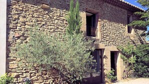 Un bâtiment en pierre, à l’aspect rustique, doté d’un petit balcon et d’une porte donnant sur un espace intérieur.