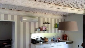 Une cuisine moderne avec un mur à rayures, des armoires blanches, une lampe suspendue et une cuisinière encastrée.