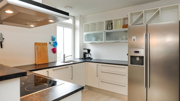 Eine moderne Küche mit einem Edelstahl-Kühlschrank, einer Kaffeemaschine und einem integrierten Wasserspender.