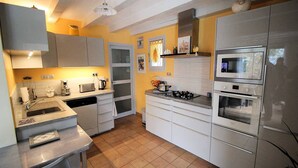 Une cuisine compacte équipée d’un évier, d’une cuisinière, d’un four à micro-ondes et d’un four traditionnel. Elle comprend également des placards et un plan de travail.