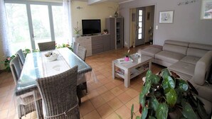 Un salon spacieux comprenant un coin repas, un canapé et un téléviseur.