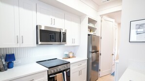 A modern kitchen with white cabinets, stainless steel appliances, and a countertop with a blue lamp and kitchen essentials. - PatioPad~UltraWalkable~Fenced~Pets~Design2Delight! (Raleigh)