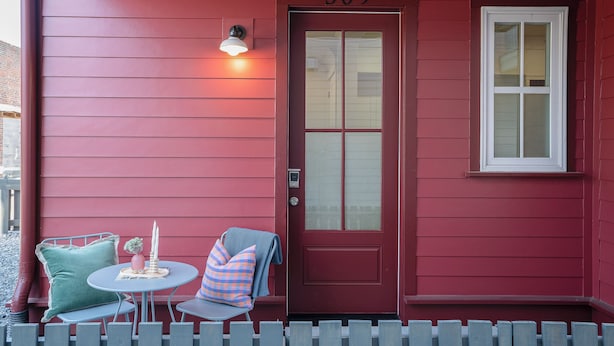 A red house with the number 309, a door, a window, and a small table with chairs and a vase. - PatioPad~UltraWalkable~Fenced~Pets~Design2Delight! (Raleigh)