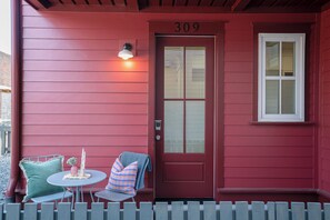 Une maison rouge portant le numéro 309, avec une porte, une fenêtre, une petite table, des chaises et un vase.