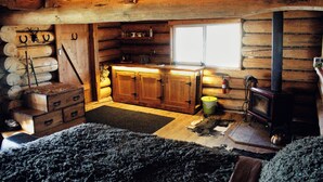 Een houten blokhut interieur met een kast, een open haard en een raam.