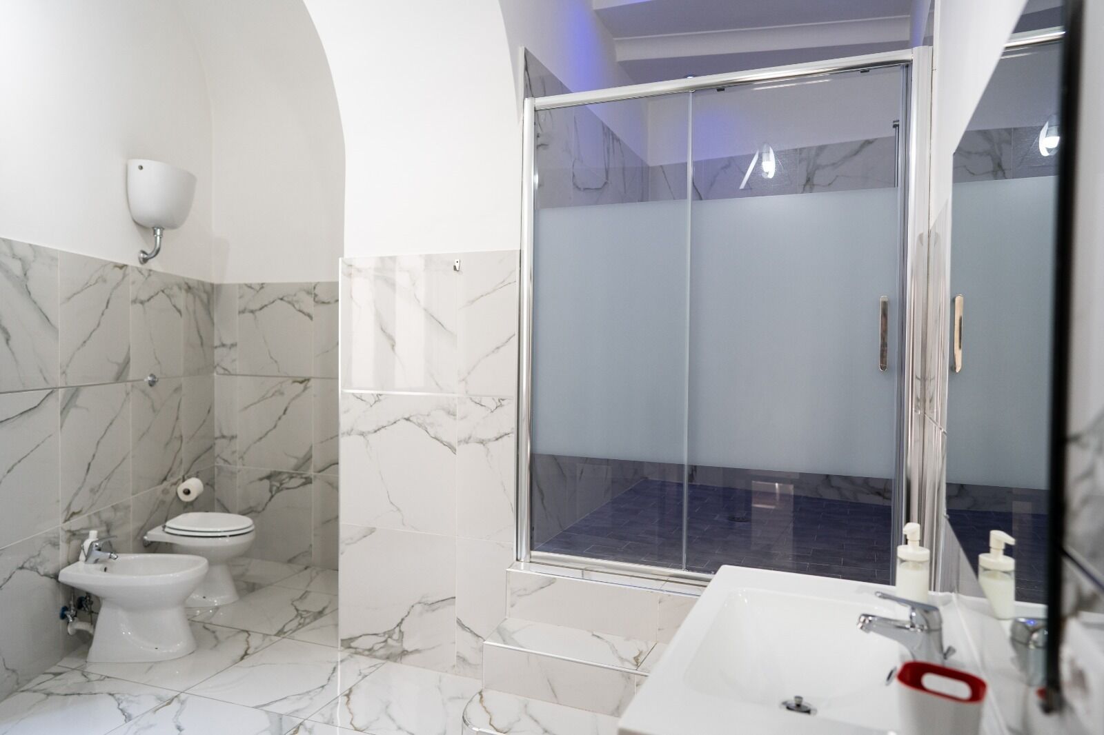 A modern bathroom with a toilet, bidet, and shower area.