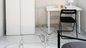 A room with a white wardrobe, a small white table with a lamp, a chair, and a bed. - San Felice Palace (Naples)