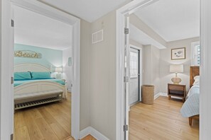 A bedroom with a bed, bedside table, lamp, and a wall with a decorative sign.