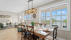 A dining area with a large table, chairs, and a hanging light fixture.