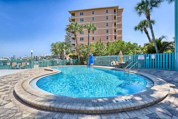 A swimming pool with a brick border, a blue cover, and a sign indicating a depth of 8 feet.