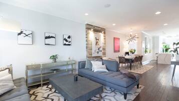 A modern living room with a grey sofa, a coffee table, and a dining area with a table and chairs.