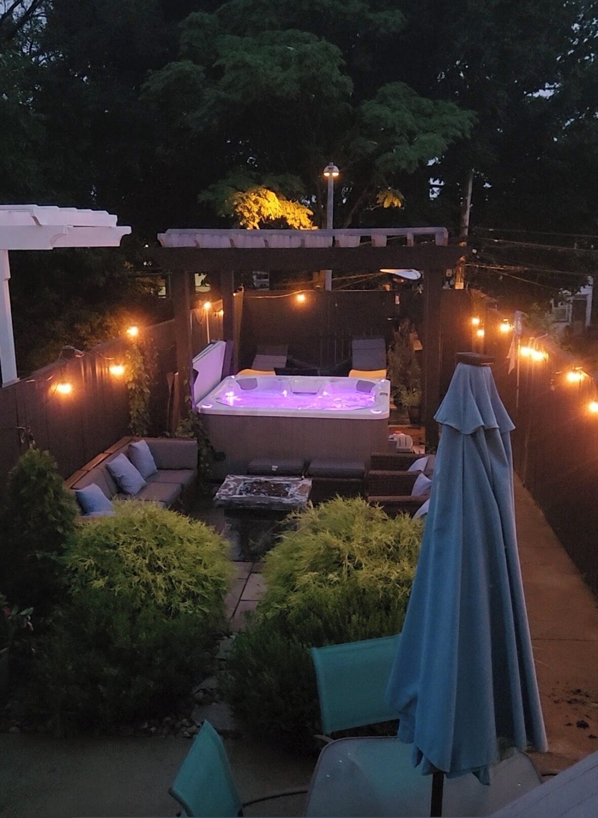 An outdoor hot tub area with seating and string lights.