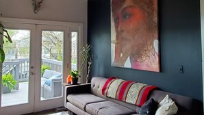 Ein modernes Wohnzimmer mit Holzboden, einem großen abstrakten Gemälde, einem grauen Sofa und einem Glastisch.