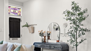 Een woonkamer met een bank, een bijzettafeltje, een potplant en een open haard.