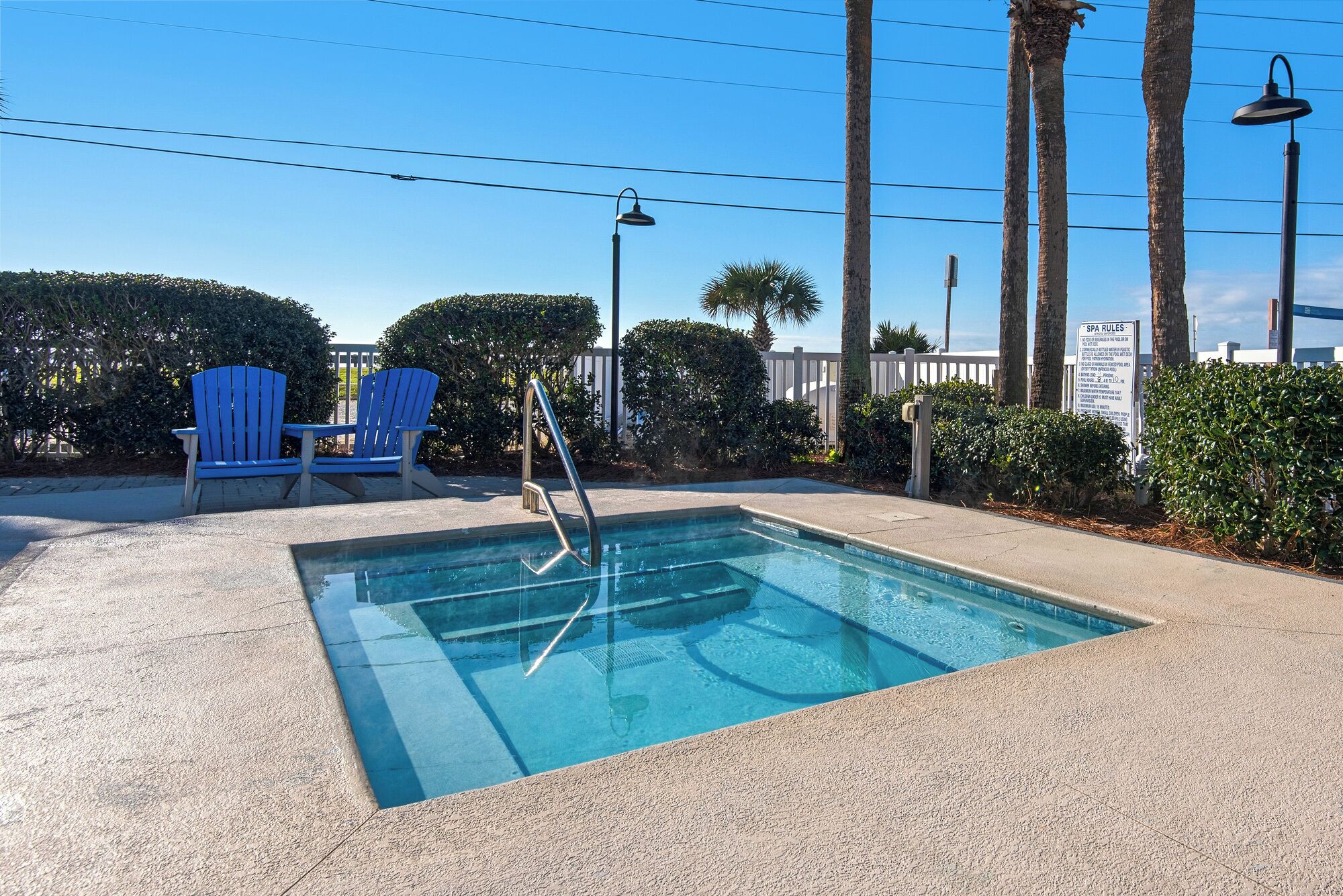 A pool area with a blue chair, a ladder, and a sign about spa rules.