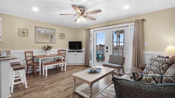 A spacious living area with a dining table, chairs, a sofa, a TV, and a ceiling fan.
