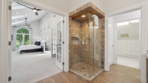 A spacious bedroom with a large bed, a walk-in closet, and a glass-enclosed shower area. - Lakeside Living - Firepit, Outdoor Fireplace, Kayaks, Arcade and much more! (Sherrills Ford)