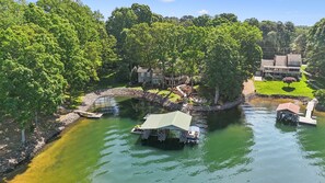 Uma propriedade à beira do lago com um cais, um barco pequeno e uma casa com um alpendre espaçoso.