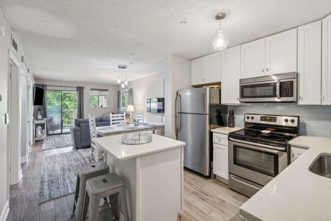 A modern kitchen with stainless steel appliances, a central island, and a dining area with a sofa and table.