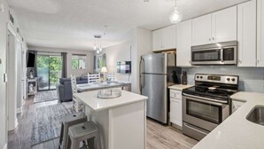 Eine moderne Küche mit Edelstahlgeräten, einer zentralen Kochinsel und einem Essbereich mit Sofa und Tisch.