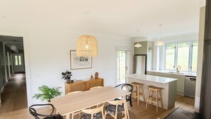 Una cocina moderna con una isla central, sillas de madera y una lámpara colgante.