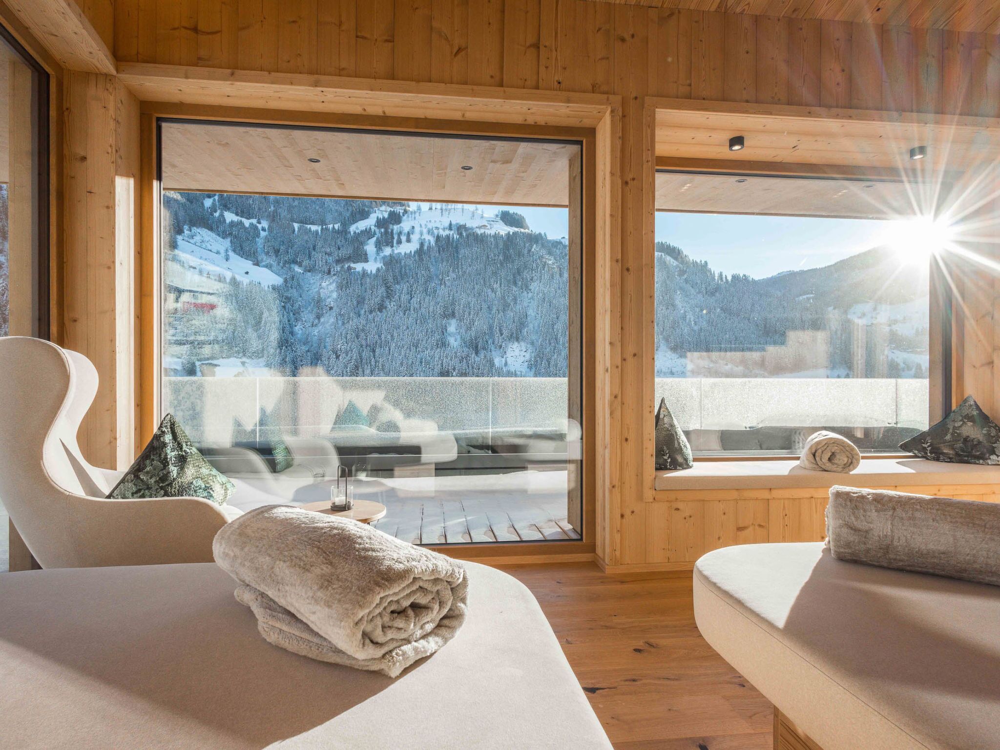 Habitació d'una cabana de fusta amb una finestra gran que ofereix una vista a la muntanya.