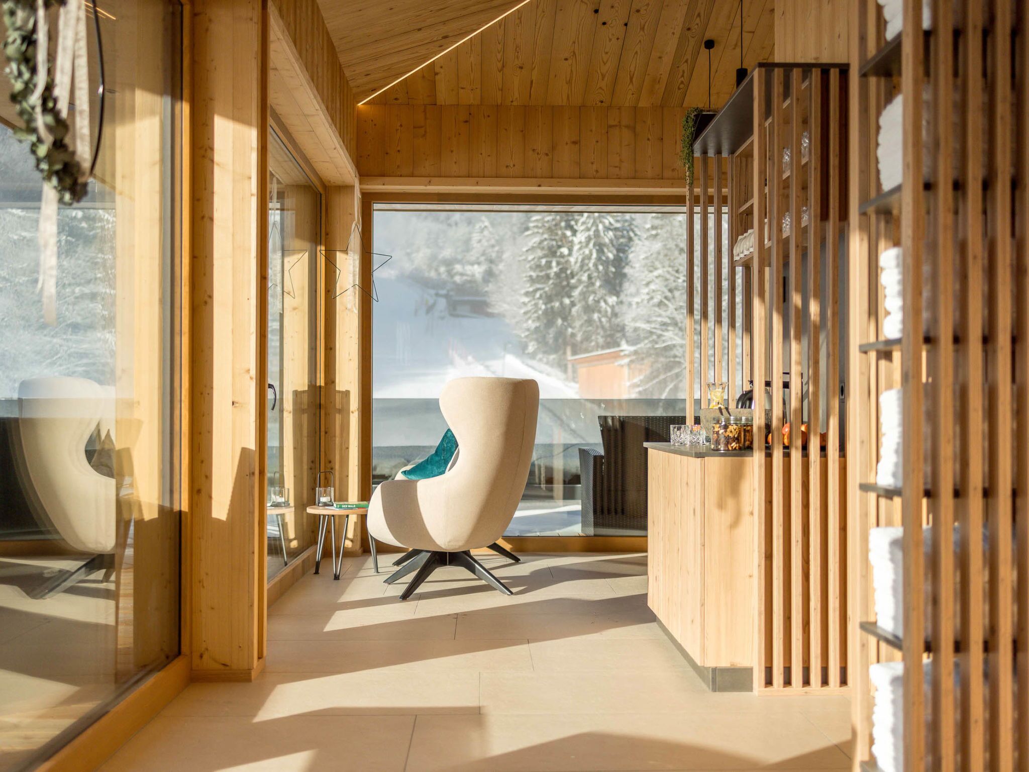 Un interior moderno con paneles de madera, una pared de vidrio y una zona de estar con una silla y una mesa.