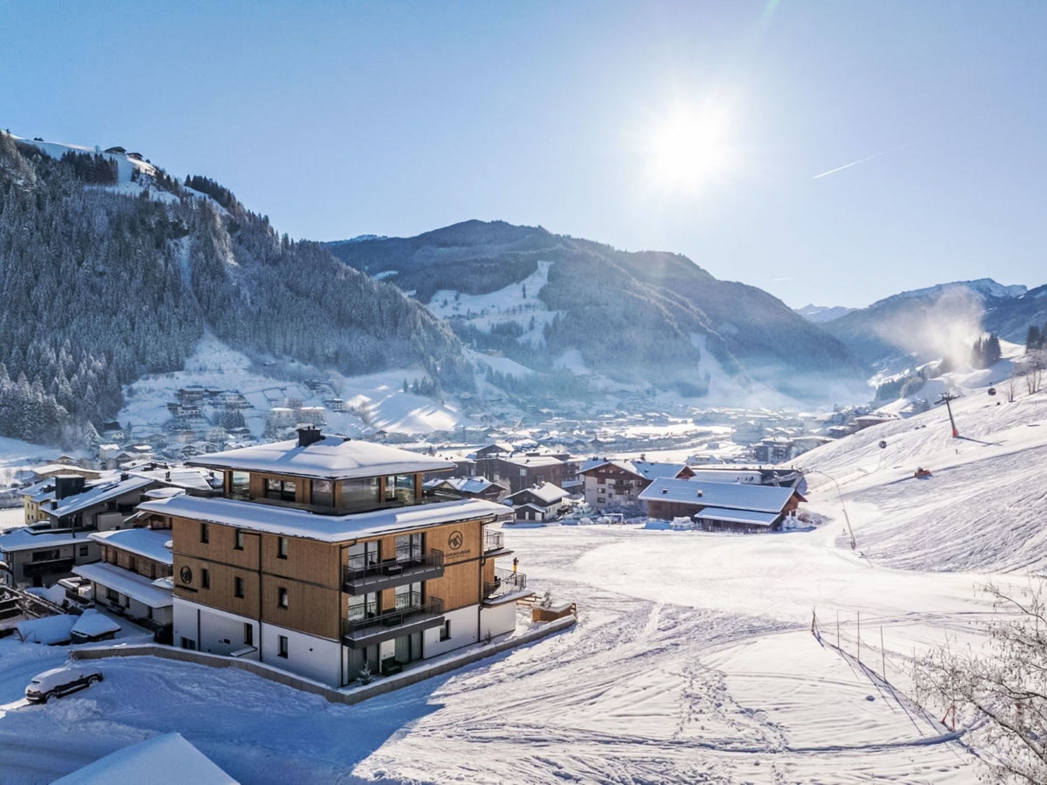 A modern building with a glass facade, surrounded by a snowy landscape and mountains in the background.