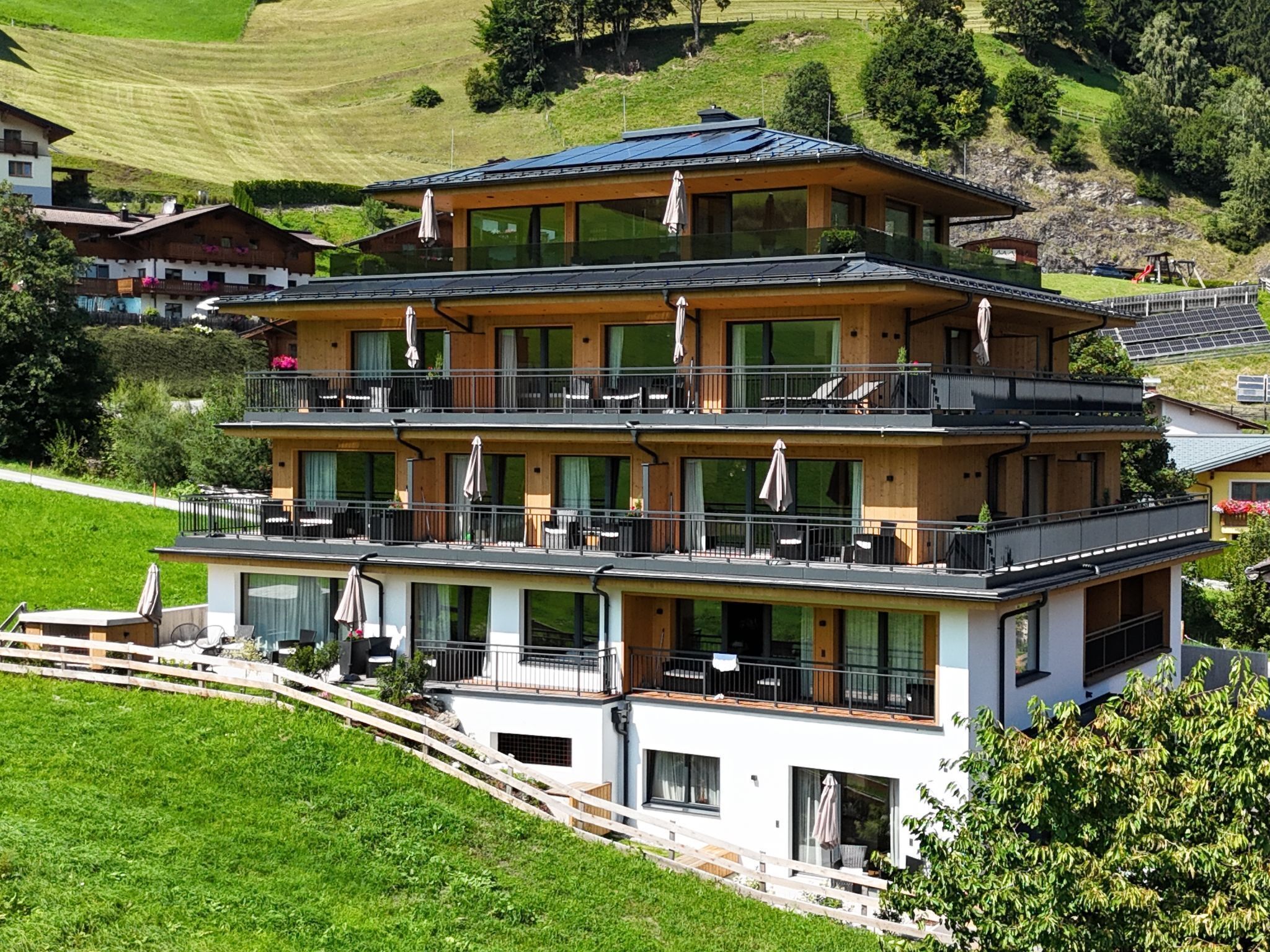 Un hôtel à plusieurs étages doté de balcons, de grandes fenêtres et d’un toit en pente.
