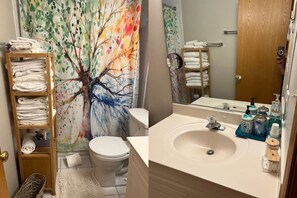 Une salle de bain équipée d’un WC, d’un lavabo, d’un miroir et d’un porte-serviettes.