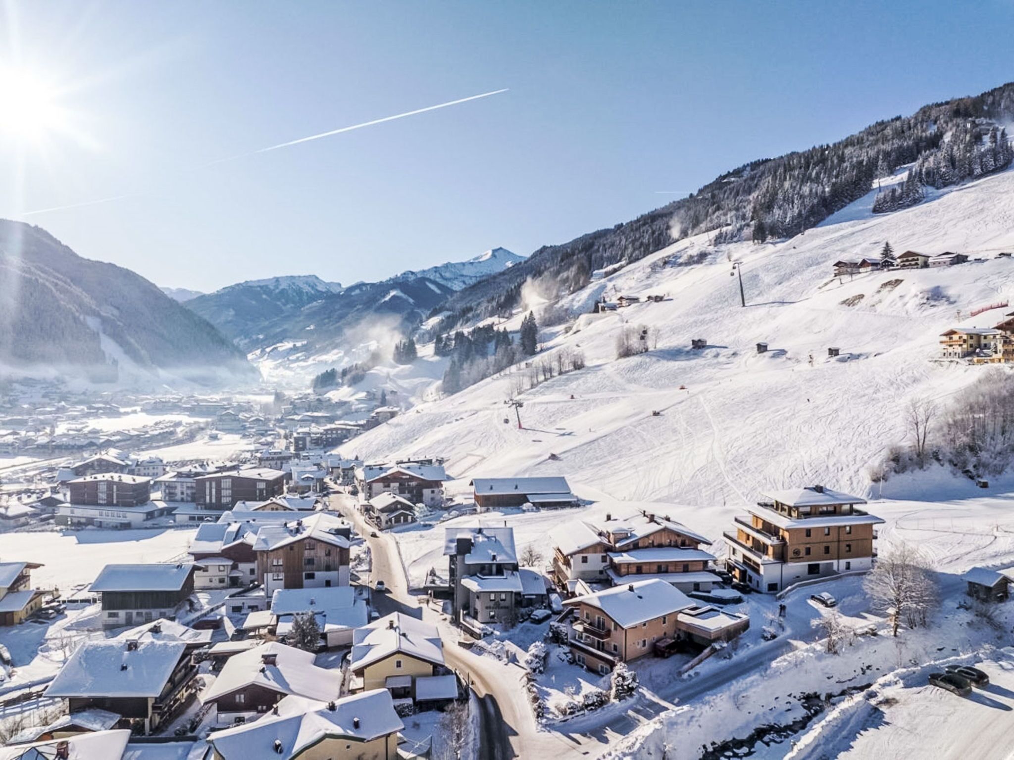 Un village enneigé avec des bâtiments et une piste de ski.