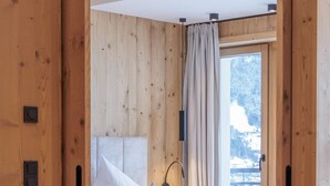Ein Schlafzimmer aus Holz mit einem Bett, einem Nachttisch und einem Fenster mit Vorhängen.