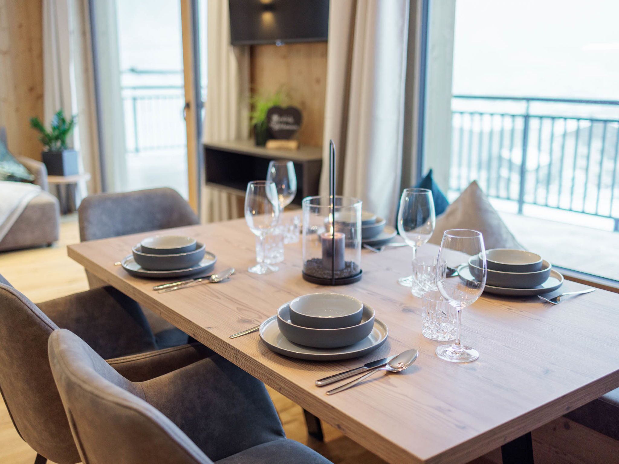 A dining table set with plates, glasses, and cutlery, with a candle centerpiece.