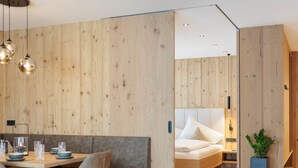 Una camera moderna con una parete in legno, un letto, un piccolo tavolo con sedie e una pianta in vaso.