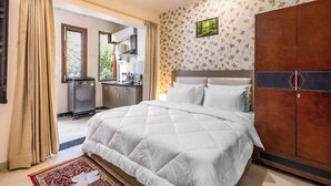A bedroom with a large bed, a wardrobe, and a kitchenette in the background. - Green Oasis , Spacious & Calm. (Gurugram)