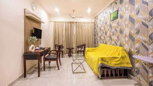 A hotel room with a bed, a desk, a chair, a TV, and a window with curtains. - Nature-inspired luxury 1 BHK (Gurugram)