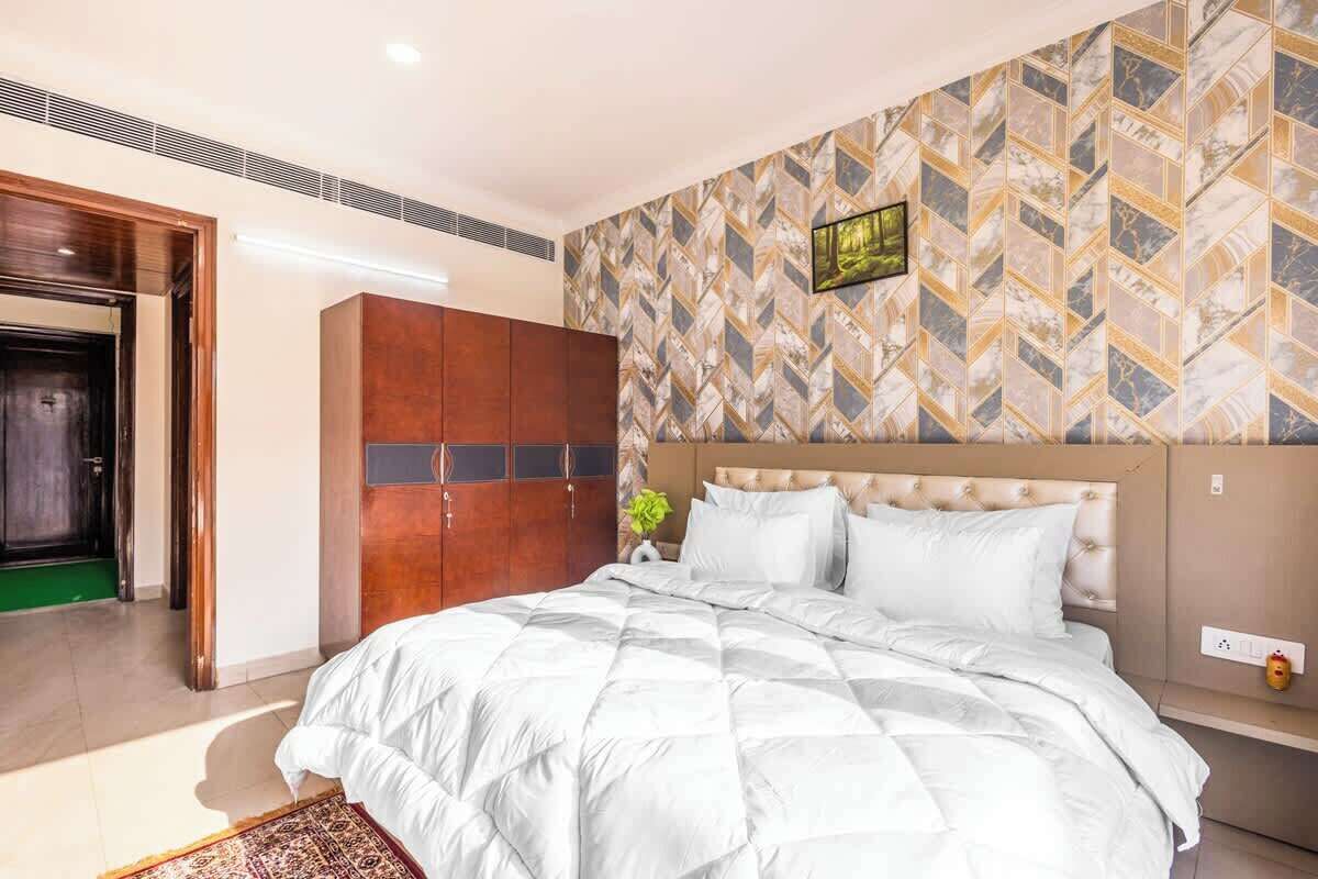 A modern hotel room with a large bed, a wardrobe, and a patterned wall.