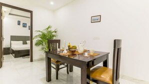 A dining area with a wooden table, chairs, and a potted plant. - Tranquil 2BHK Oasis in the Heart of Gurugram (Gurugram)