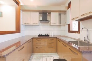 A kitchen with wooden cabinets, a gas stove, a stainless steel sink, and a window above the sink.