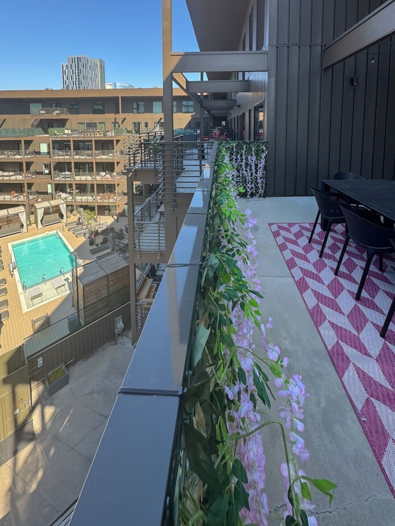Une terrasse sur le toit avec une piscine, des espaces de détente en plein air et une vue sur les bâtiments environnants.