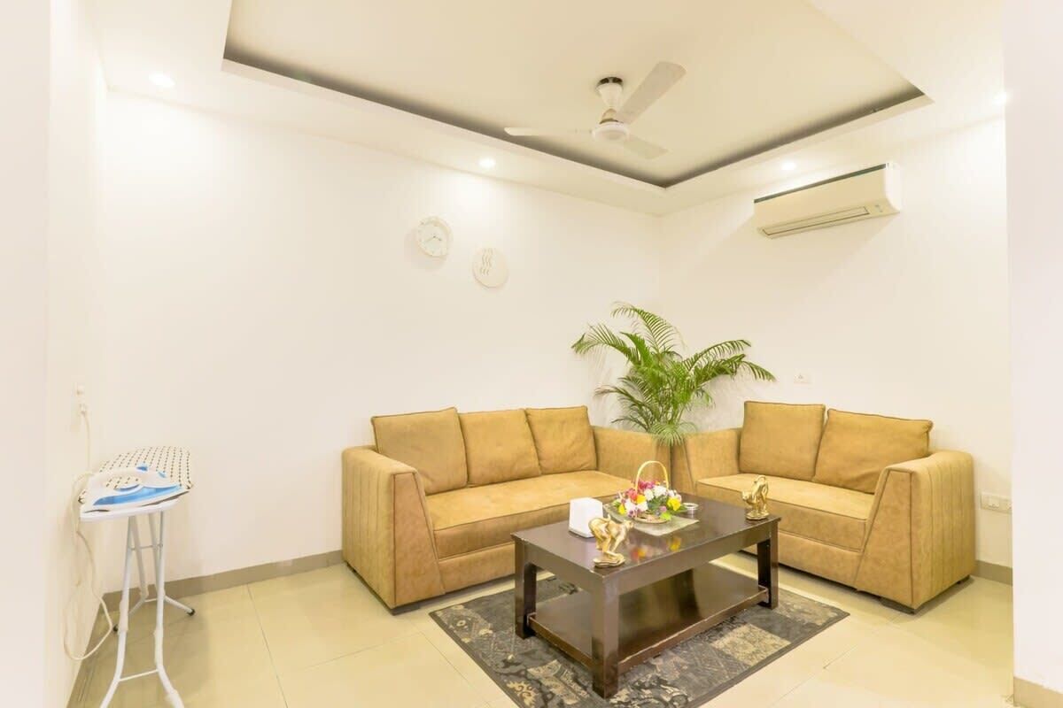 A living room with a beige sofa, a coffee table, a small side table, a plant, and a ceiling fan.