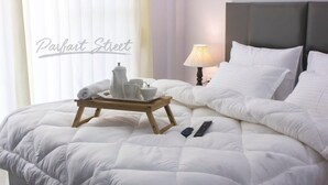 A neatly made bed with a white duvet, a tray with tea set, and a remote control on the bed. - Parfait Street retreat 2Bhk Paras Fortis Balcony (Gurugram)